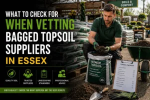 Bagged topsoil suppliers in Essex displaying premium screened topsoil bags at a landscaping supply yard, with a professional inspecting soil quality for lawn preparation, planting, and garden landscaping projects